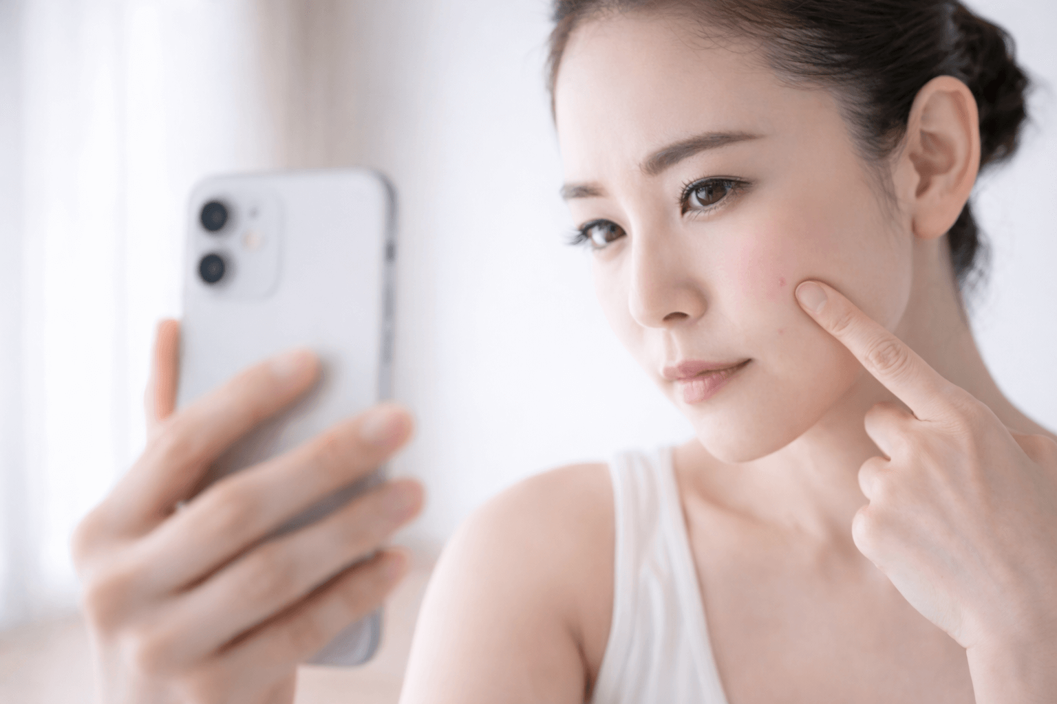 自宅でスマートフォンを使いシミや肝斑についてオンライン診療を受けている女性